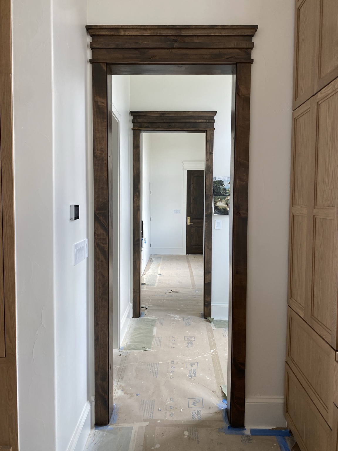 Custom stained wood trim framing a sequence of interior openings during construction